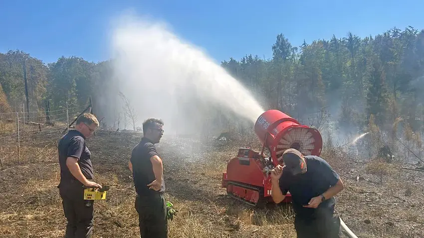Hier haben Einsatzkräfte den mobilen, fernsteuerbaren Wasserwerfer der Soester Kameraden in Stellung gebracht. Bis zu 60 Meter weit erzeugt er einen breiten Wasservorhang und durchfeuchtet das Gebiet großflächig. · Foto: Feuerwehr Möhnesee