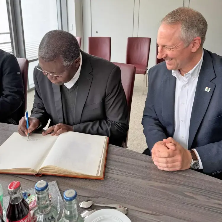 Foto: Erzbischof Ignatius Chama trägt sich ins Goldene Buch ein, Bürgermeister Wolf Blesken schaut ihm dabei zu.